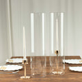 Elegant clear candle holders with gold accents on a wooden table setting.