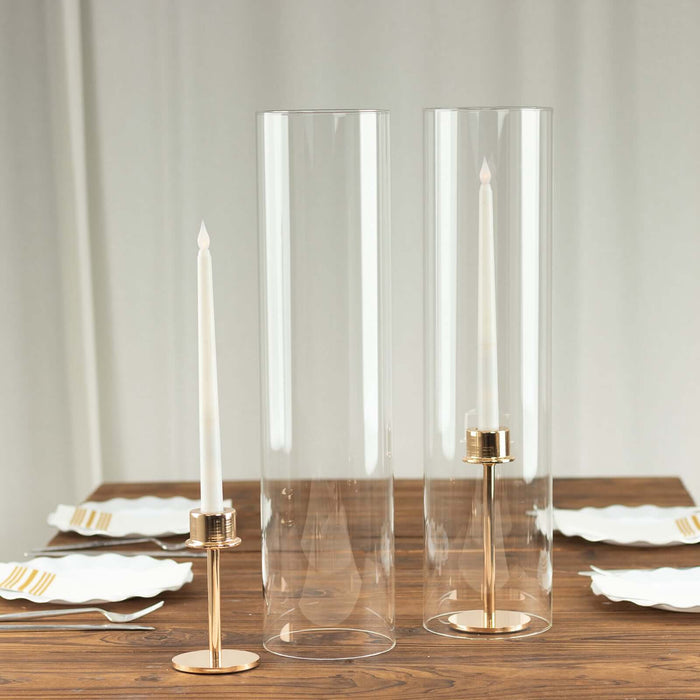 Elegant clear candle holders with gold accents on a wooden table setting.