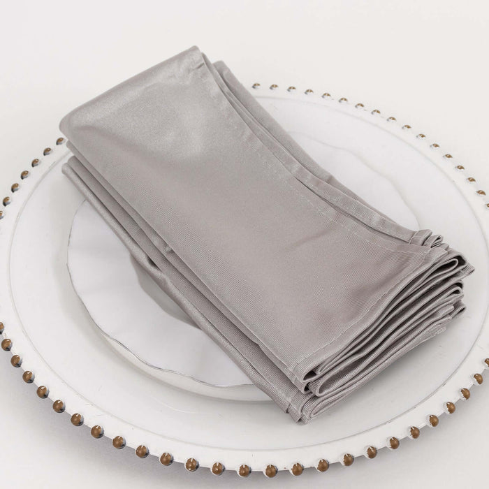 Silver satin napkins neatly stacked on a decorative plate.