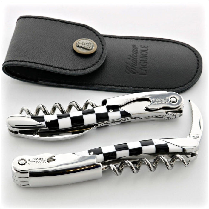 Chateau Laguiole Grand Cru Damier Corkscrew, top-down view of two corkscrews with black and white checkered handles and a black leather case. Handcrafted details, 100% Made in France.