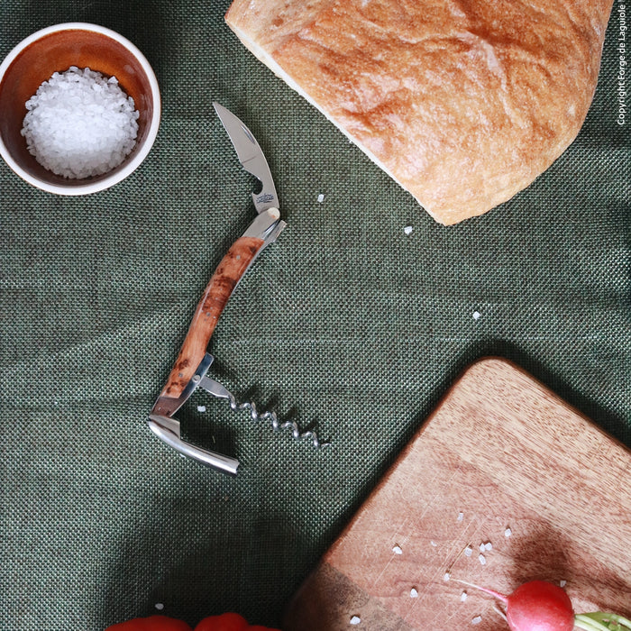 Forge de Laguiole Corkscrew Juniper, top-down view of shiny steel tool with wood handle on green cloth.