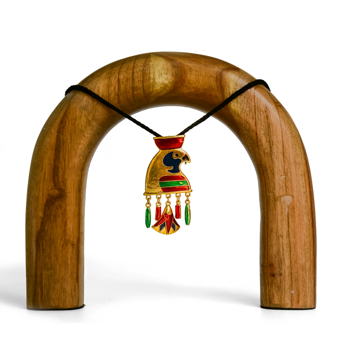 Horus depicted as a gold and black falcon adorned with red headwear, with black, red, and green details. Gold loops attach one green and one red bead decorations on either side, and Egyptian-style gold lotus ornament in the center with beautiful detailing.