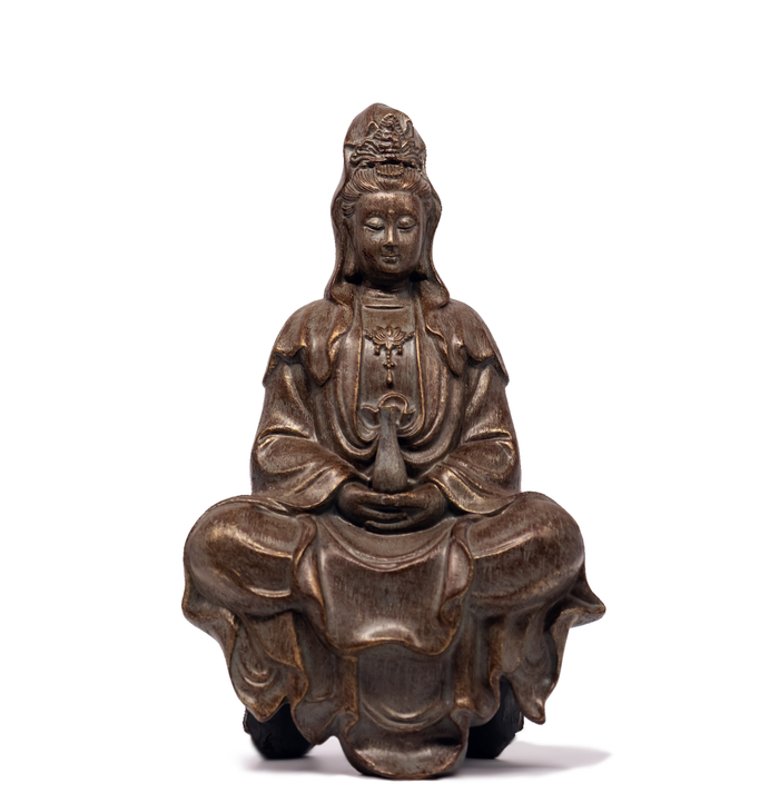 Guanyin statue with rock-like finish, holding small vase. Her eyes are closed and she is calm-looking.