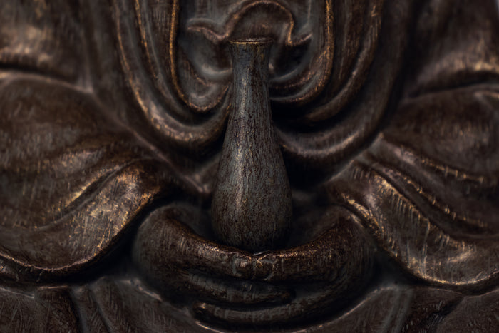 Close-up detail shot of Guanyin statue's hands around the vase, with statue "fabric" draping nicely around it.