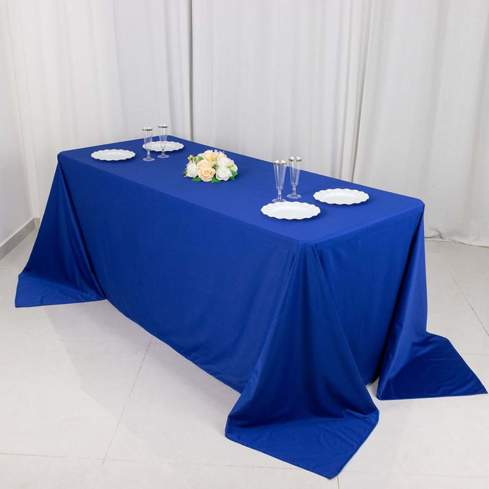 Blue tablecloth on a table set for an event with floral centerpiece and glassware.